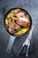 Traditional barbecue leg of lamb with lemon and tomatoes in a skillet