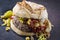 Traditional barbecue Mexican Hamburger with corn, peperoni and chili relish on a rustic black board