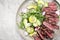 Traditional barbecue skirt steak sliced with salad and avocado on a modern design plate