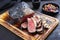 Traditional barbecue smoked wagyu sirloin cap of rump beef sliced with ratatouille and herbs on a rustic wooden board