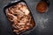 Traditional barbecue wagyu torn to bits pulled beef in hot chili sauce in a roasting dish on a rustic board