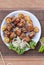 A traditional barbeque chicken kabab in a white plate along vegetables on a wooden table top view