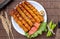 A traditional barbeque chicken kabab in a white plate along vegetables on a wooden table top view