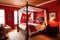 traditional bedroom, with canopy bed and warm red accent wall