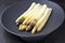 Traditional blanched white asparagus with purple heads on a cast iron design plate with copy space