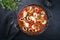 Traditional Brazilian fish stew moqueca capixaba with fish filet and squid rings in tomato sauce in a rustic pan