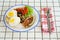 traditional breakfast on a plate on a table with a plaid tablecloth.