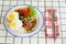 traditional breakfast on a plate on a table with a plaid tablecloth.