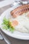 Traditional breakfast with sausages, fried eggs with ground black pepper and bread