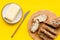 Traditional breakfast. Wholegrain bread on cutting board with butter, slice of bread on yellow background top view