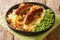 Traditional British cuisine fried sausages with mashed potatoes, onion gravy and green peas close-up in a plate. horizontal