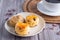 Traditional British scones on a plate with a teacup on a wooden table with a purple flower blurred background