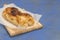 Traditional Bulgarian cheese pastry Banitsa on wooden board on dark blue background