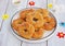 Traditional buttery twisted Italian Easter cookies with multicolored sugar decor on a white plate on a white wooden background.