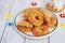 Traditional buttery twisted Italian Easter cookies with multicolored sugar decor on a white plate on a white wooden background.