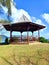 Traditional Caribbean gazebo. Wooden pergola in French West Indies garden under tropical blue sky. Decorative furniture and