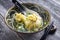 Traditional Caucasian manti offered in a soup in a modern design bowl on a wooden board