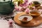 Traditional ceremony. Cup of brewed tea, teapot, dried leaves and sakura flowers on tiled table, closeup