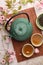 Traditional ceremony. Cup of brewed tea, teapot, dried leaves and sakura flowers on tiled table, flat lay