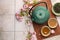 Traditional ceremony. Cup of brewed tea, teapot, dried leaves and sakura flowers on tiled table, flat lay with space for text