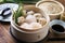 Traditional Chinese Dim Sum offered in bamboo steamer on a wooden table