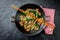 Traditional chinese mongolian beef stir fry in chinese cast iron wok with cooking chopsticks, stone slate background