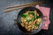 Traditional chinese mongolian beef stir fry in chinese cast iron wok with cooking chopsticks, stone slate background