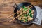 Traditional chinese mongolian beef stir fry in chinese cast iron wok with cooking chopsticks, wooden background. Top