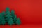 Traditional Christmas festive background with cartoon paper spruces as forest on red backdrop in elegant baby style, copy space.