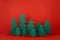 Traditional Christmas festive background with cartoon paper spruces as forest on red backdrop in elegant baby style. New Year.