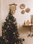 Traditional Christmas tree with red and gold baubles and festive lights in decorated boho room