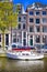 Traditional City Yacht in One of Amsterdam Canals In Front of Old Dutch Houses