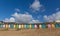 Traditional colourful English seaside scene with beach huts on the beach and blue sky with pastel colours