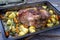 Traditional corned pot pork roast with potatoes, carrots and fennel in clear sauce on a rustic metal tray