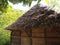 Traditional country house or barn with thatched, dry grassy roof in summer in the forest. The craft of building a roof