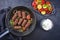 Traditional Croatian cevapi spicy meat ball rolls with BBQ vegetable and tzatziki in a skillet