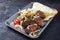 Traditional Croatian cevapi spicy meat ball rolls with cabbage carrot salad, pita bread and hot ajvar sauce in a metal tray