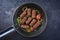 Traditional Croatian cevapi spicy meat ball rolls with tomatoes and onion rings in a skillet