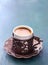 Traditional cup of turkish coffee with foam on dark blue-green wooden background