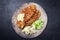 Traditional deep-fried schnitzel with potato and cucumber salad on a rustic design plate