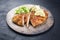 Traditional deep-fried schnitzel sliced with potato and cucumber salad on a rustic design plate