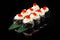 Traditional delicious fresh sushi roll set on a black background with reflection. Sushi roll with rice, nori, cream cheese, tobiko