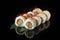 Traditional delicious fresh sushi roll set on a black background with reflection. Sushi roll with rice, nori, cream cheese, tobiko