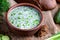 Traditional dish - cold soup `okroshka` in a clay bowl on a wooden background. Dietary refreshing dish.