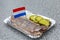 Traditional Dutch appetizer of herring, pickles and onions on a paper plate in an outdoor cafe. Close-up