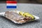 Traditional Dutch appetizer on a paper portion plate: herring, cucumber and onions. A popular dish in street cafes. Close-up