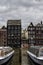 Traditional dutch medieval buildings in along the canal side and parked pleasure boats .Amsterdam, Netherlands.