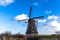 Traditional dutch windmill near the canal. Netherlands. Old windmill stands on the banks of the canal, and water pumps. White clou