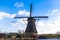 Traditional dutch windmill near the canal. Netherlands. Old windmill stands on the banks of the canal, and water pumps. White clou