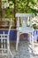 Traditional Egyptian metal tea table and white wooden chair on background of green climber plant